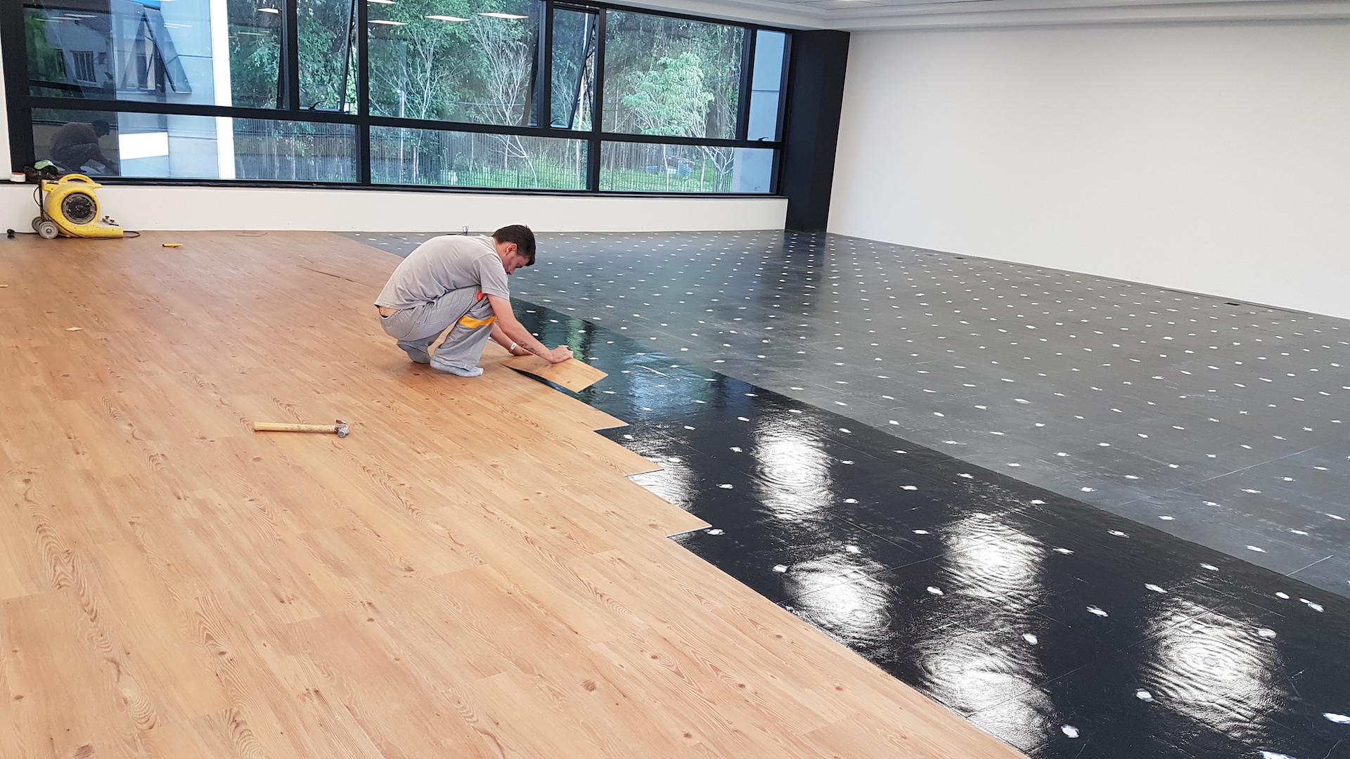 Instalador da Instalfloor assentando piso vinílico em réguas em um escritório